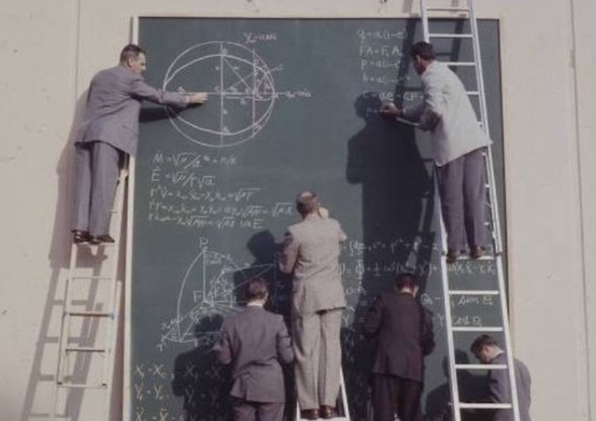 Vintage photo of scientists on tall ladders, writing equations on a chalkboard